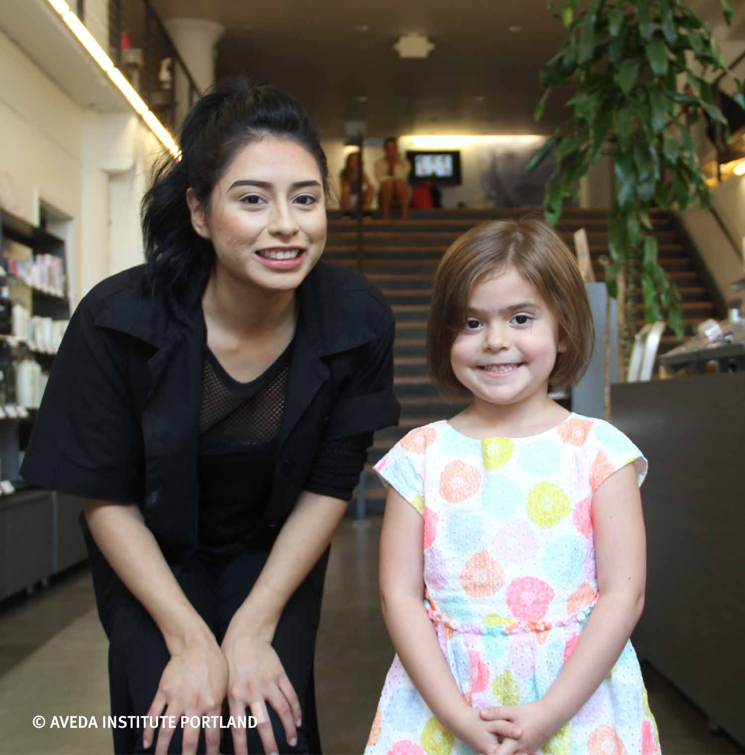 Image of a student with a small child during our annual cuts for kids event at aveda institute portland and vancouver campus