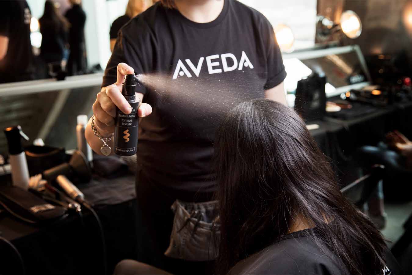 Image of a student styling hair at aveda institute portland