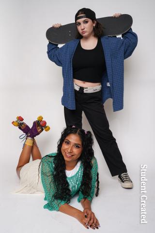 Image of a student photoshoot with two student models. One wearing sporty clothes, backwards hat and a skateboards over their shoulder. The other model is laying down on their stomach with roller skates on their feet and a smile on their face. 