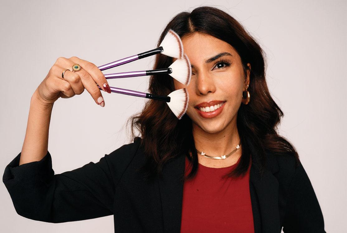 Image of an Aveda student holding makeup brushes